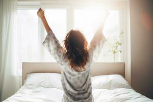 mujer despertó arriba en el cama y su levantado ambos brazos. foto