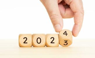 New year concept. Hand flips Wooden Blocks from 2023 to 2024 year. Copy space photo