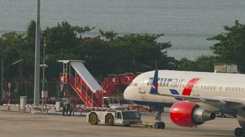 PHUKET, THAILAND FEBRUARY 26, 2023 - Towing Azur Air plane Boeing 757, RA73071 at Phuket Airport, medium shot. Airplane against the background of the sea video