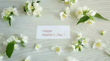 Wooden background with blooming beautiful white jasmine and congratulations for mother. video