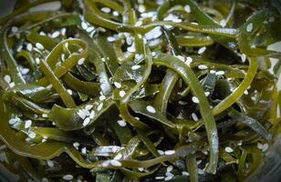 Seaweed salad. Asian cuisine. Seaweed kelp sprinkled with sesame seeds, close-up, soft focus. Laminari photo