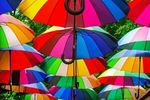 Park alley is decorated with multi-colored umbrellas. Canopy made of rainbow umbrellas. photo