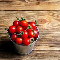 small bucket of fresh red cherry tomatoes on a wooden table top. Top view. Harvest.  Natural food. copy space photo