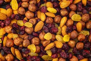 Mixed dried fruits background. Healthy snacks. Almonds, raisins, hazelnuts, cranberries. Assorted nuts and dried berries. View from above. Stack. Healthy food concept photo