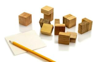 Wooden puzzle made up of parts isolated on a white background. A sheet of paper and a pencil. The solution of the problem. Layout for presentation. photo