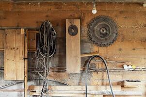 Wall in the carpentry workshop with many tools and planks of wood, as well as some hand tools. Rustic workshop.set of circular saw photo