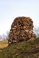 Chopped firewood for kindling and heating the house. pile of firewood, stacked in a circle, a well. Timber harvesting. Rural areas. photo