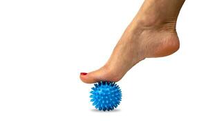Relaxation of the muscles of the foot with a spiky silicone massage ball, physiotherapy at home. Relieve foot fatigue after wearing high-heeled shoes. photo