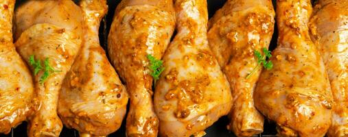 Raw chicken drumsticks marinated red with turmeric, garlic, mustard and parsley. Lined with chicken on a wire rack, ready to bake. B-B-Q. Home kitchen. Top view. photo