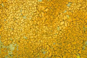 background of the old oily yellow paint is cracked by the weather. Texture. photo