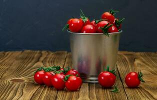 Little bucket of fresh red cherry tomatoes on a wooden table top. View side. Harvest. Natural food. Copy space photo