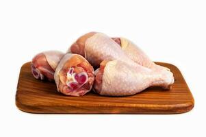 pollo crudo carne espinilla, baquetas en de madera corte tablero. aislado. de cerca foto