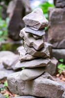 Close-up of a stack of stones in perfect balance in a mountain forest. Rock pyramid, rock balancing art. Meditation, balance, peace. Hobby. Vertical photo. photo