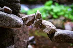 Rock bridge, pyramid, rock balancing art. Close-up of a stack of stones in perfect balance in a mountain forest. Sun rays. Meditation, balance, peace. Hobby. photo