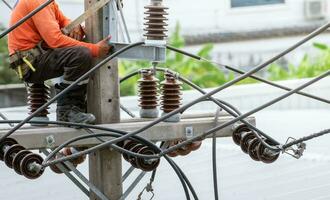 High voltage power line maintenance. Electrician at work. Electrical technician working on electric pole. High voltage power line construction. Danger of wiring and electrical wires. Work with safety. photo