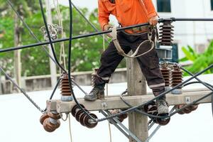 High voltage power line maintenance. Electrician at work. Electrical technician working on electric pole. High voltage power line construction. Danger of wiring and electrical wires. Work with safety. photo