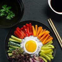 Close-up of a Korean dish, with a variety of appetizers with vegetables and eggs. Diet. bibimbap. Top view. Round plate. photo