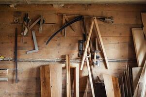 Wall in the carpentry workshop with many tools and planks of wood, as well as some hand tools. Rustic workshop. photo