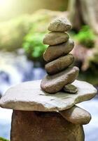 Rock pyramid, rock balancing art. Close-up of a stack of stones in perfect balance in a mountain forest. Sun rays. Meditation, balance, peace. Hobby. Vertical photo. photo