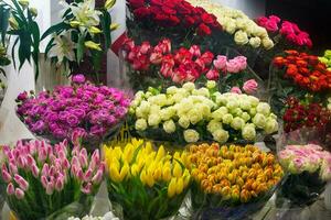 Bouquet of colorful roses, Eustoma, Tulip, other different flowers at entrance flower store. Showcase. Beautiful flowers for catalog, online store. Flower business. Concept flower store and delivery. photo