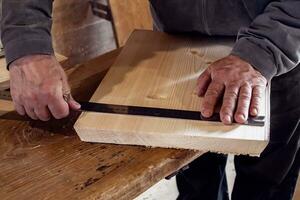 male carpenter marks out a wooden board with a ruler and pencil in his home workshop. working with wood. photo