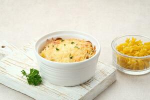 Baked macaroni and cheese on a white bowl with parmesan and herbs photo