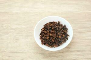 Dried cloves or cengkeh, dried herbs served in small bowl photo