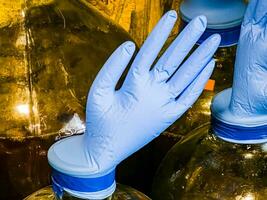 The correct fermentation process, making homemade wine. Glass bottles with huge blue inflated gloves on a wooden background. photo