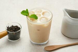 Milk tea with brown sugar syrup in a tall glass with ice and mint leaf photo