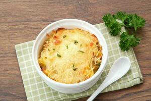 Baked macaroni and cheese on a white bowl with parmesan and herbs photo