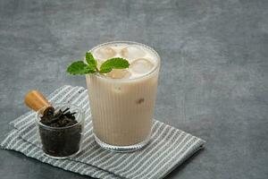 Milk tea with brown sugar syrup in a tall glass with ice and mint leaf photo