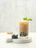 Boba milk tea with brown sugar syrup in a tall glass with ice and mint leaf photo