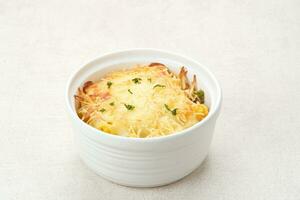 Baked macaroni and cheese on a white bowl with parmesan and herbs photo