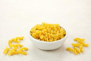 Raw Macaroni pasta served on white bowl photo