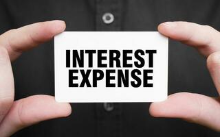 Businessman holding a card with text interest expense , business concept photo