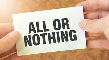 ALL OR NOTHING word inscription on white card paper sheet in hands of a businessman. photo