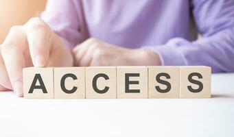 Businessman hand holding wooden cube block with ACCESS business word on table background. photo