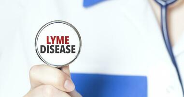 firmar Lyme enfermedad y mano con estetoscopio de médico médico foto