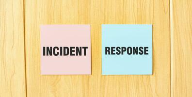 Inscription INCIDENT RESPONSE on pink and blue square sticky sticker on wooden wall photo