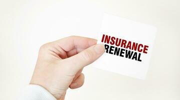 Businessman holding a card with text INSURANCE RENEWAL, business concept photo