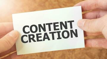 CONTENT CREATION word inscription on white card paper sheet in hands of a businessman. photo