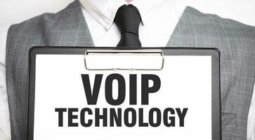 Businessman holding sheet of paper with a message VOIP TECHNOLOGY photo