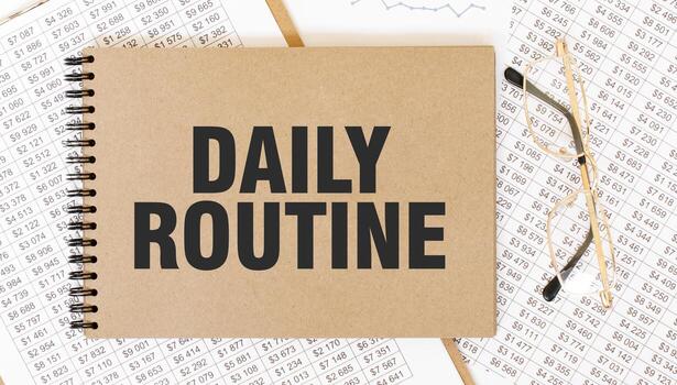 Craft colour notepad with text DAILY ROUTINE. Notepad with eyeglasses and text documents. Business concept photo