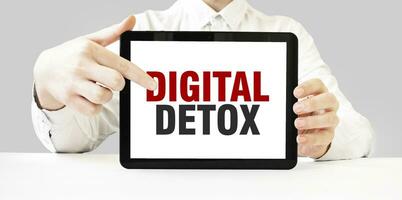 Text DIGITAL DETOX on tablet display in businessman hands on the white background. Business concept photo