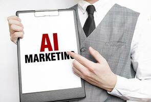 AI MARKETING inscription on a notebook in the hands of a businessman on a gray background, a man points with a finger to the text photo