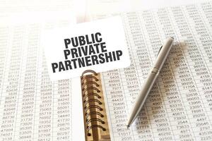 Text PUBLIC PRIVATE PARTNERSHIP on paper card, pen, financial documentation on table photo