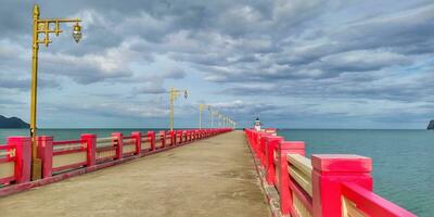 a long pier with red poles and a light post photo