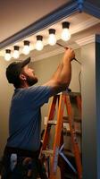 Electrician installing new light fixtures in a home photo