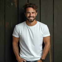 A joyful man stands with his hands in his pockets, wearing a white mock up t shirt. photo