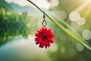 a red flower hanging from a branch near a lake. AI-Generated photo